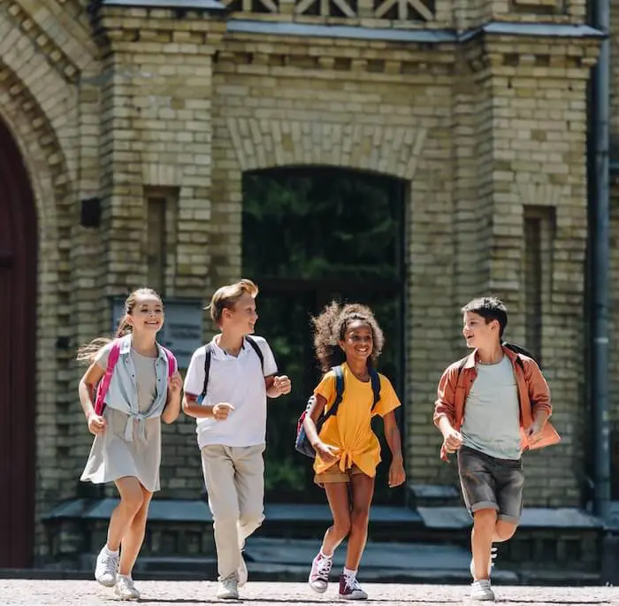 Children running with backpacks outdoors