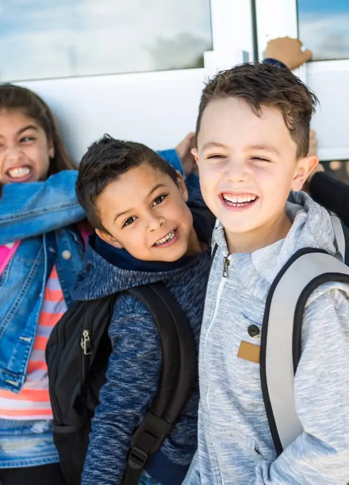 Smiling kids with backpacks hugging